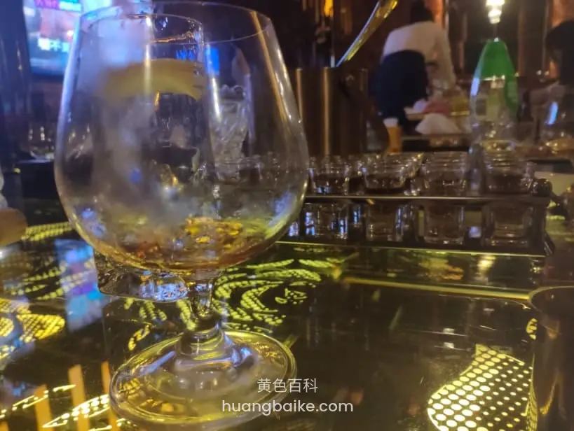 酒杯里冰块柠檬和残酒,吧台倒映灯光图案