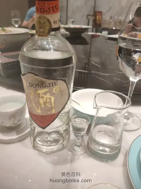 餐桌上的董酒酒瓶,旁边摆酒杯和茶具,标签上写董酒