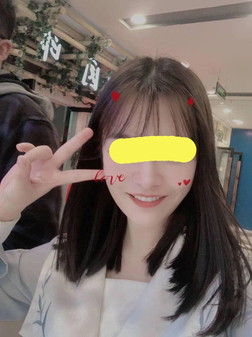 女生对着镜头比剪刀手,头顶两个小红心,love
