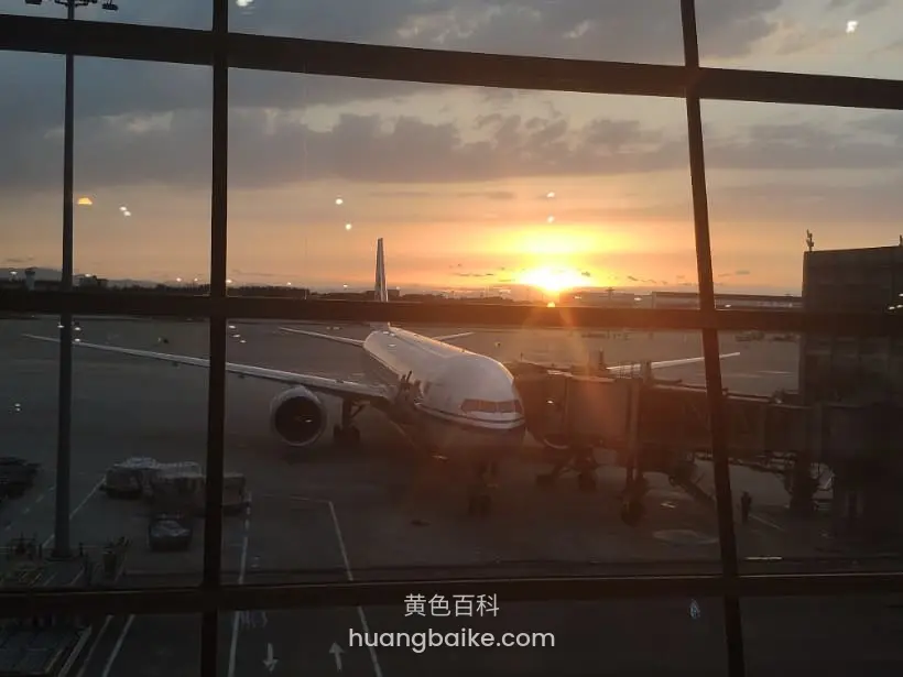 机场落地窗前看飞机,远处夕阳正落