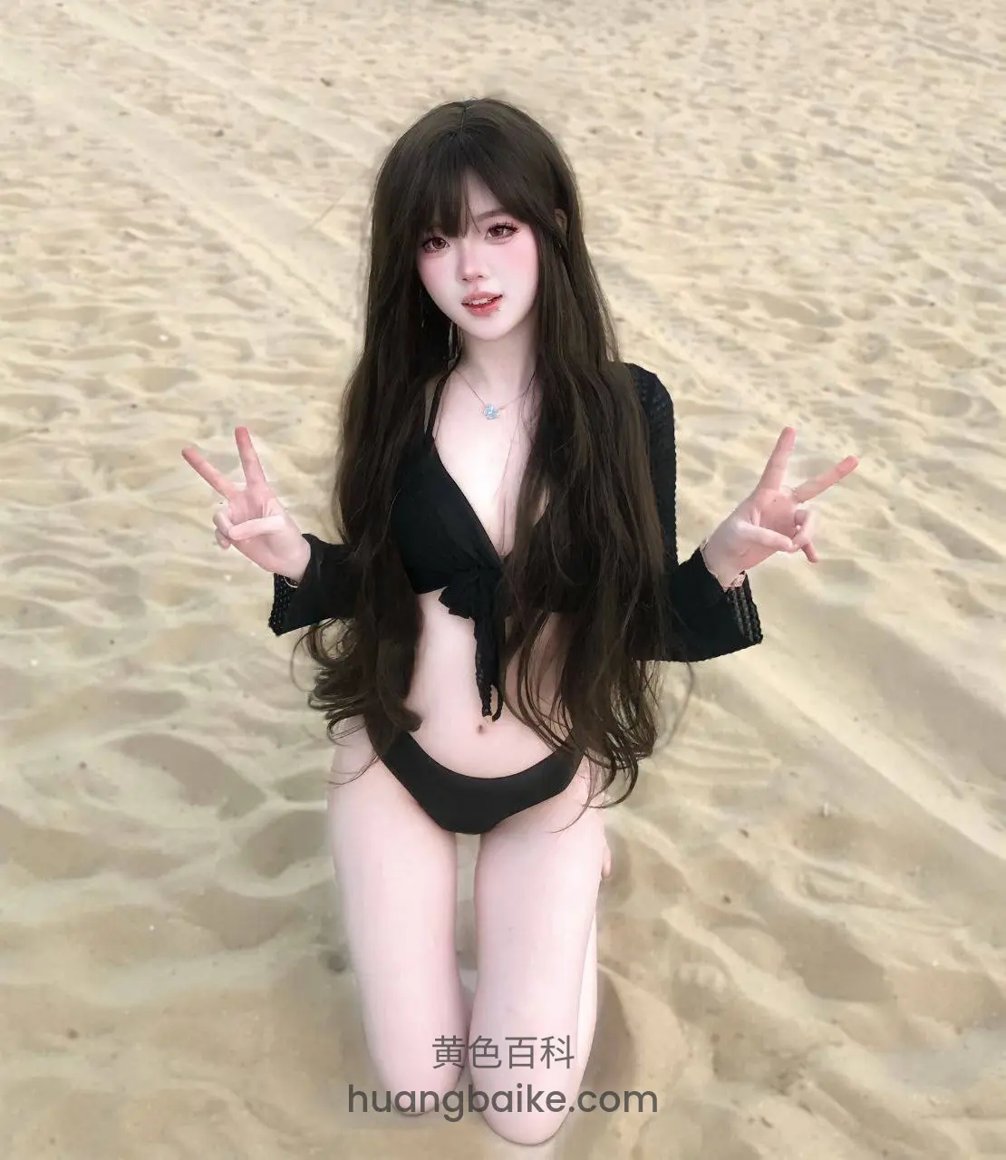 海滩跪姿双手比耶，身后一片沙地