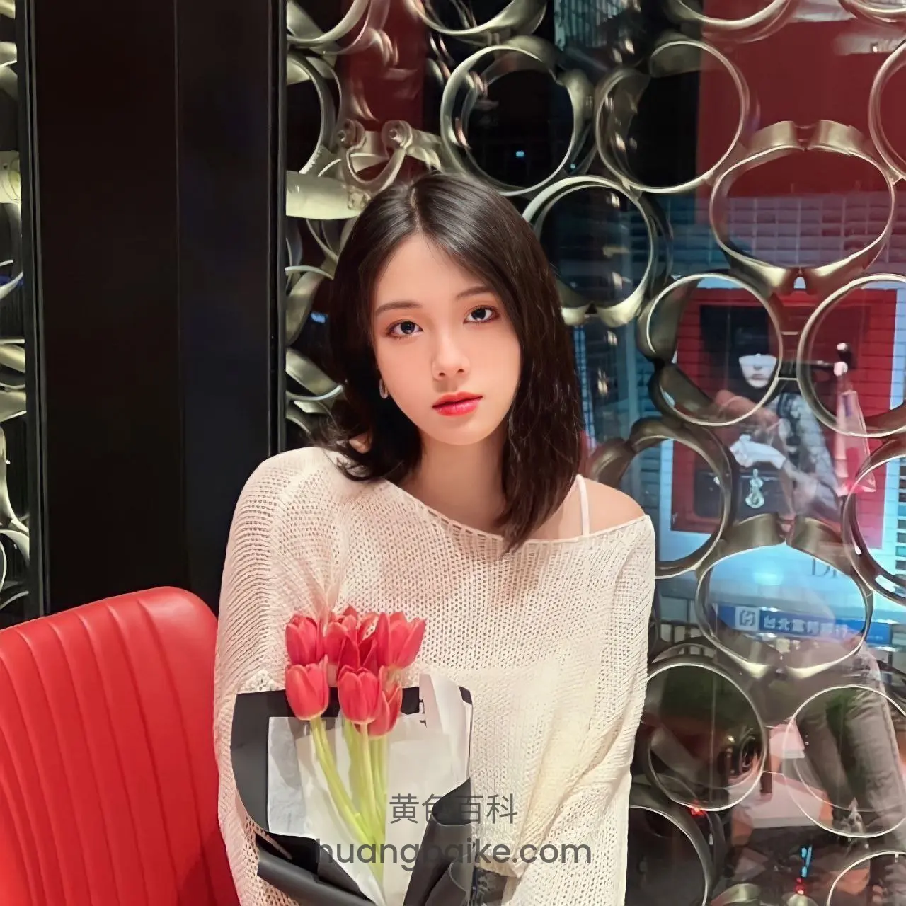 红色座椅上，拿着红玫瑰花束