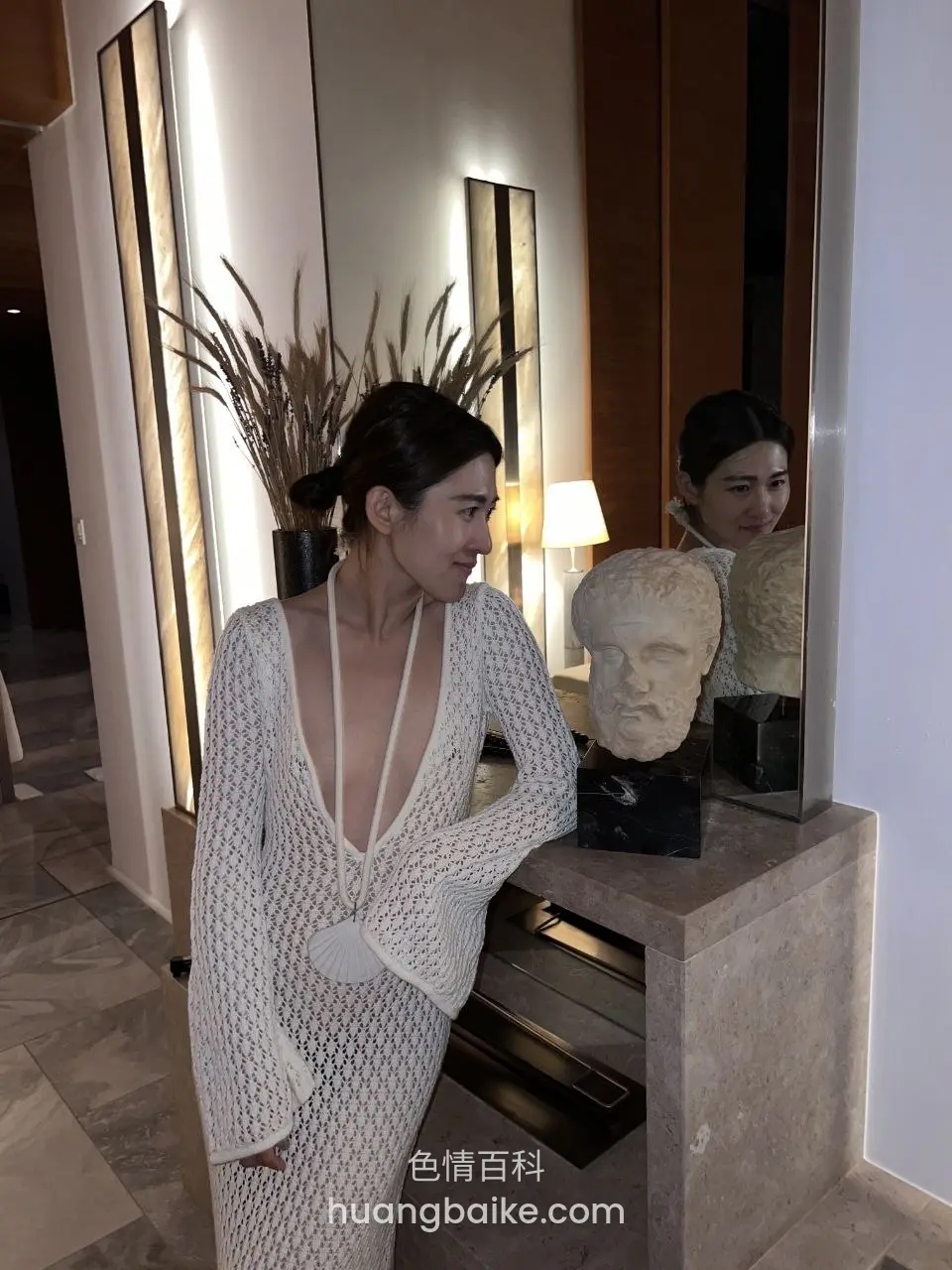 酒店大厅里，石台上摆着雕塑和镜子
