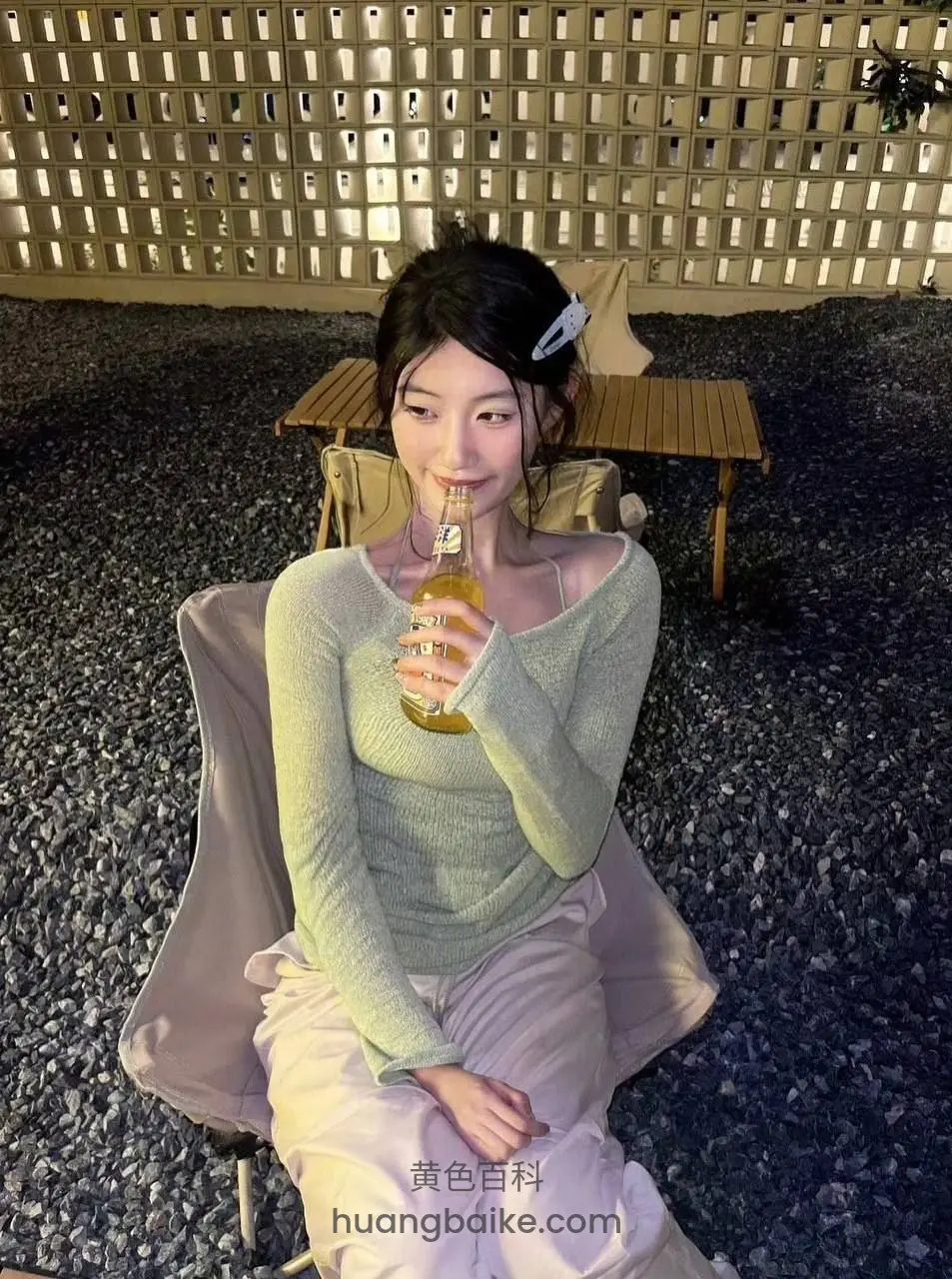 夜晚露台椅子坐着，拿着玻璃瓶喝饮料