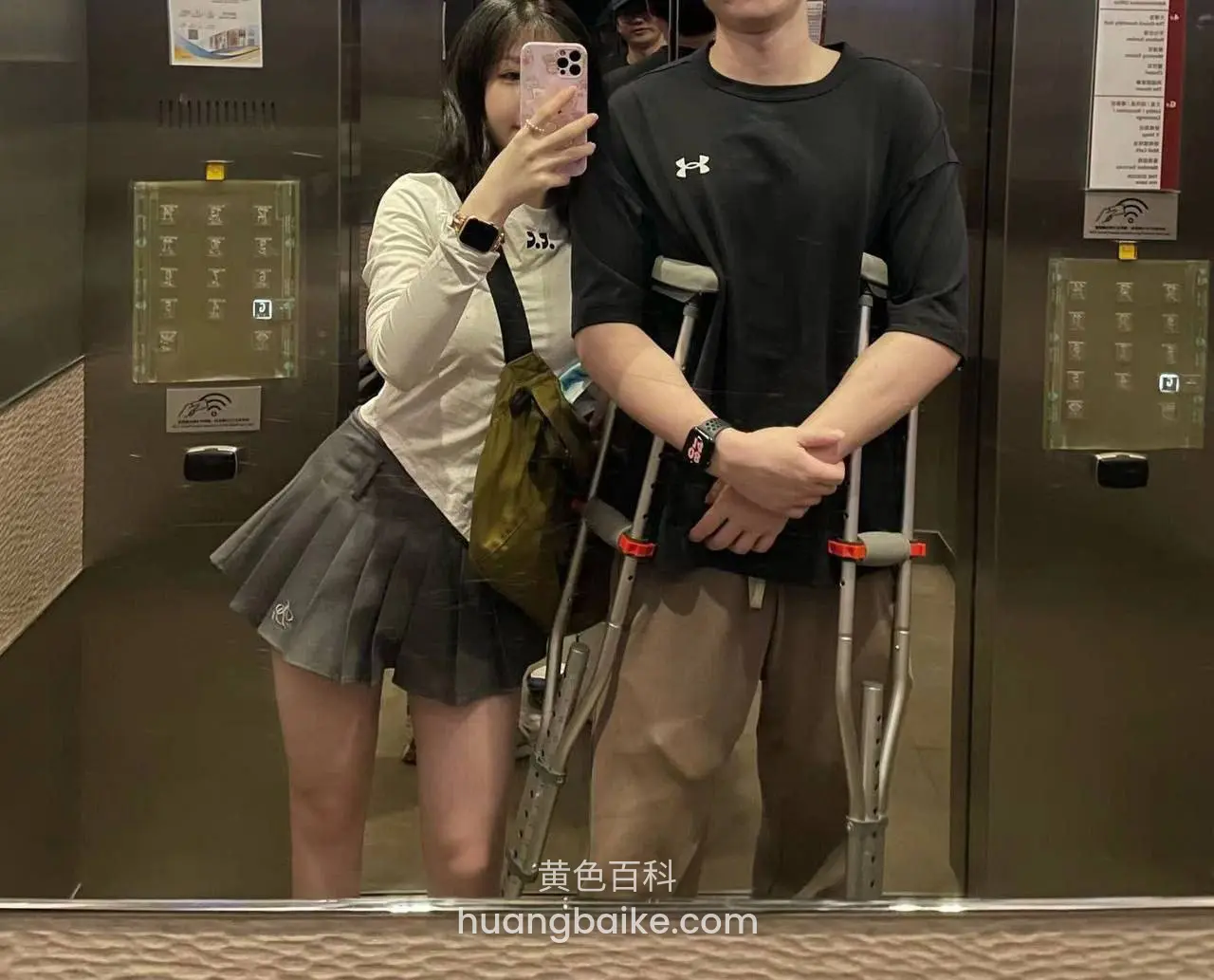 电梯镜子里举手机自拍，旁边男生拄拐