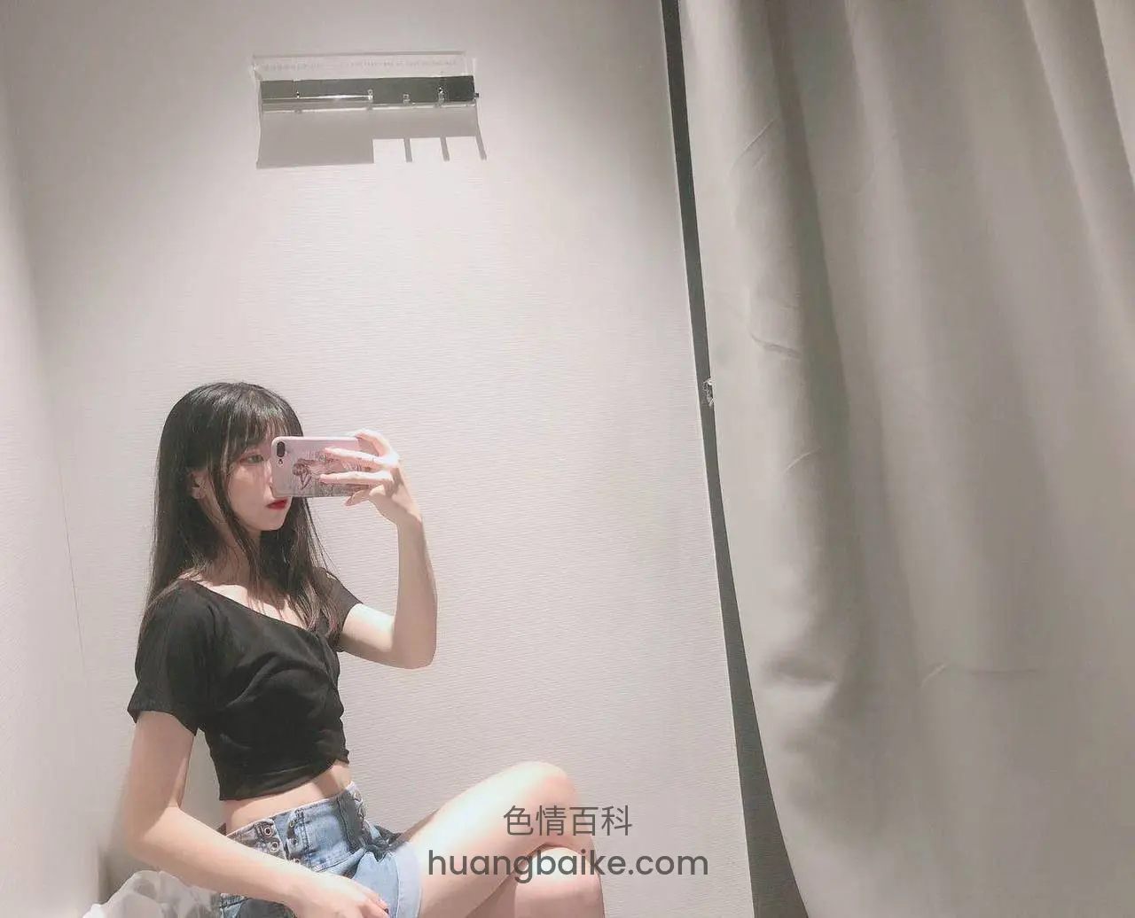 试衣间里举着粉色手机