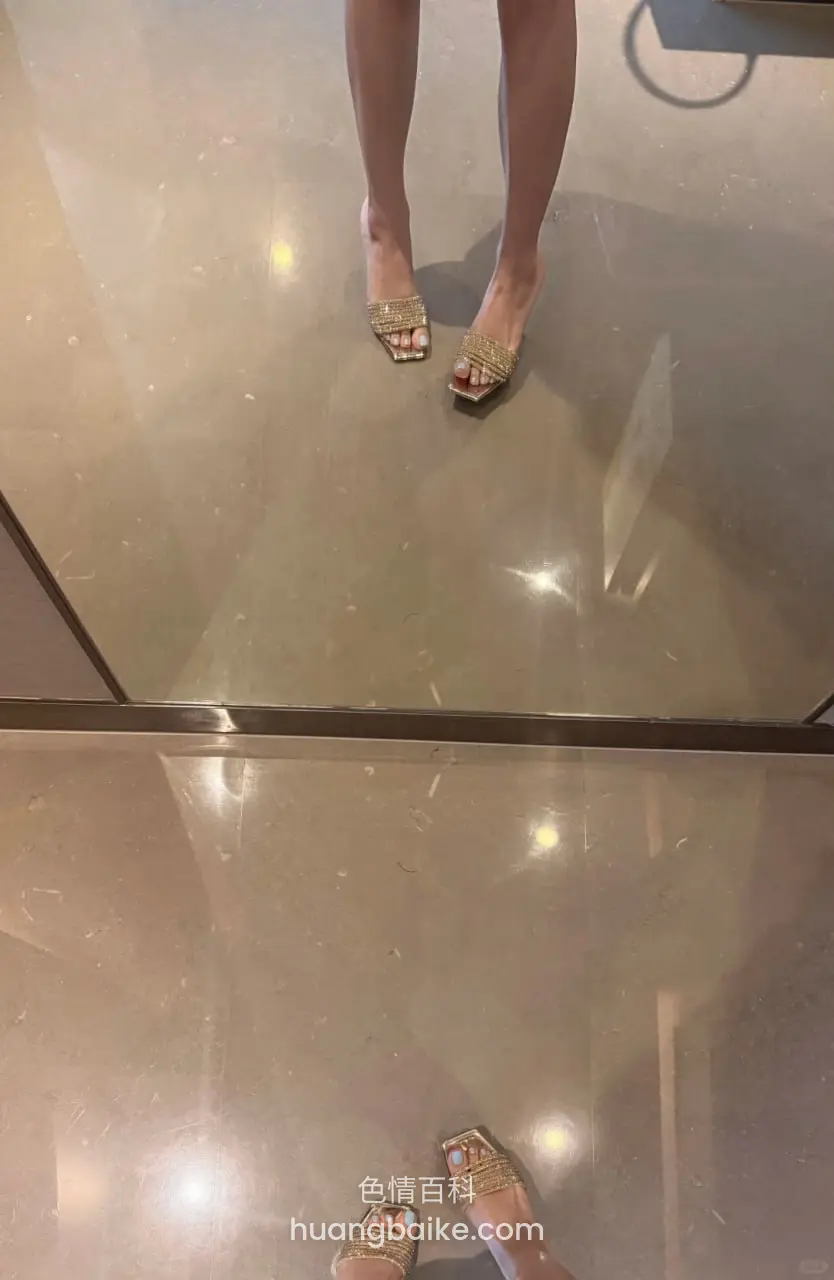 镜面地板上两双金色凉鞋，影子拉长着