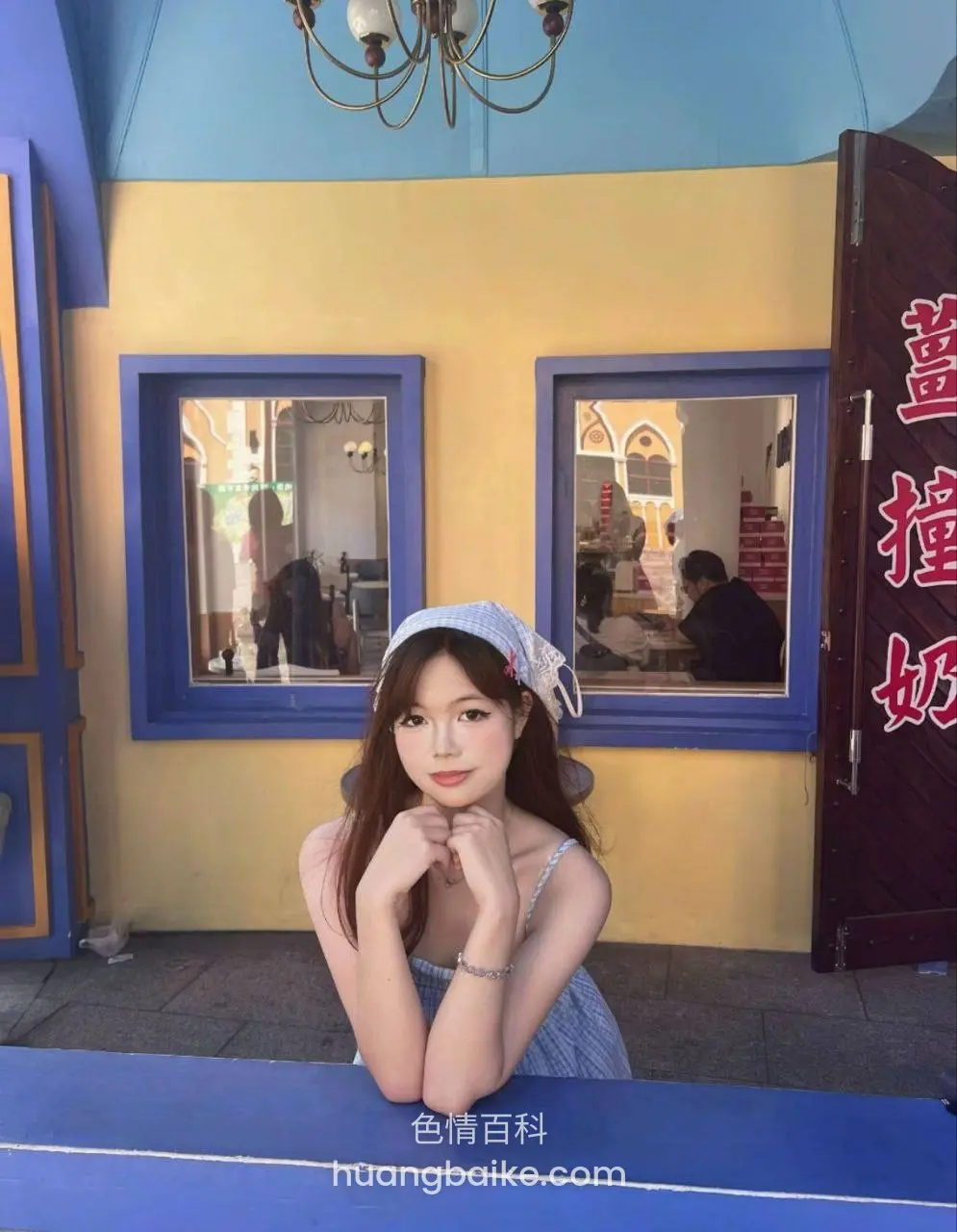 彩色建筑前双手托下巴，身后红字招牌