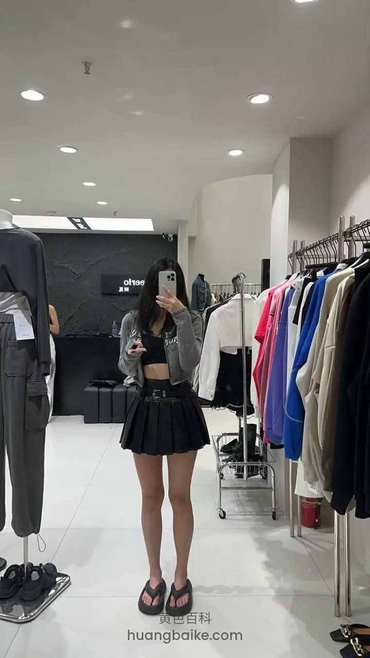 服装店里拿着手机拍，身后挂满衣服