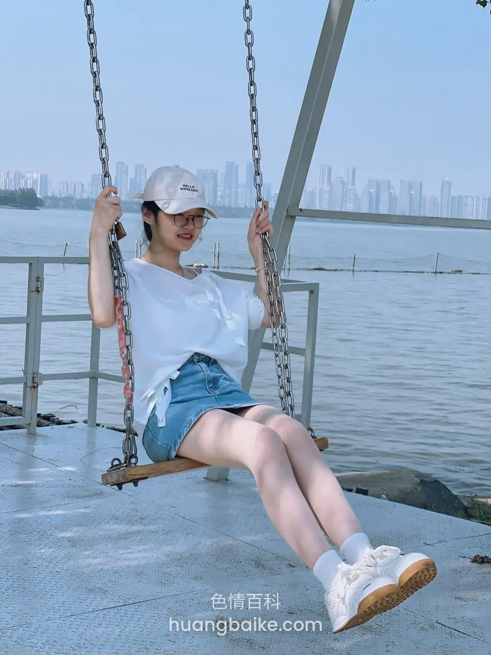 湖边秋千上坐着握链条看远处城市 skyline