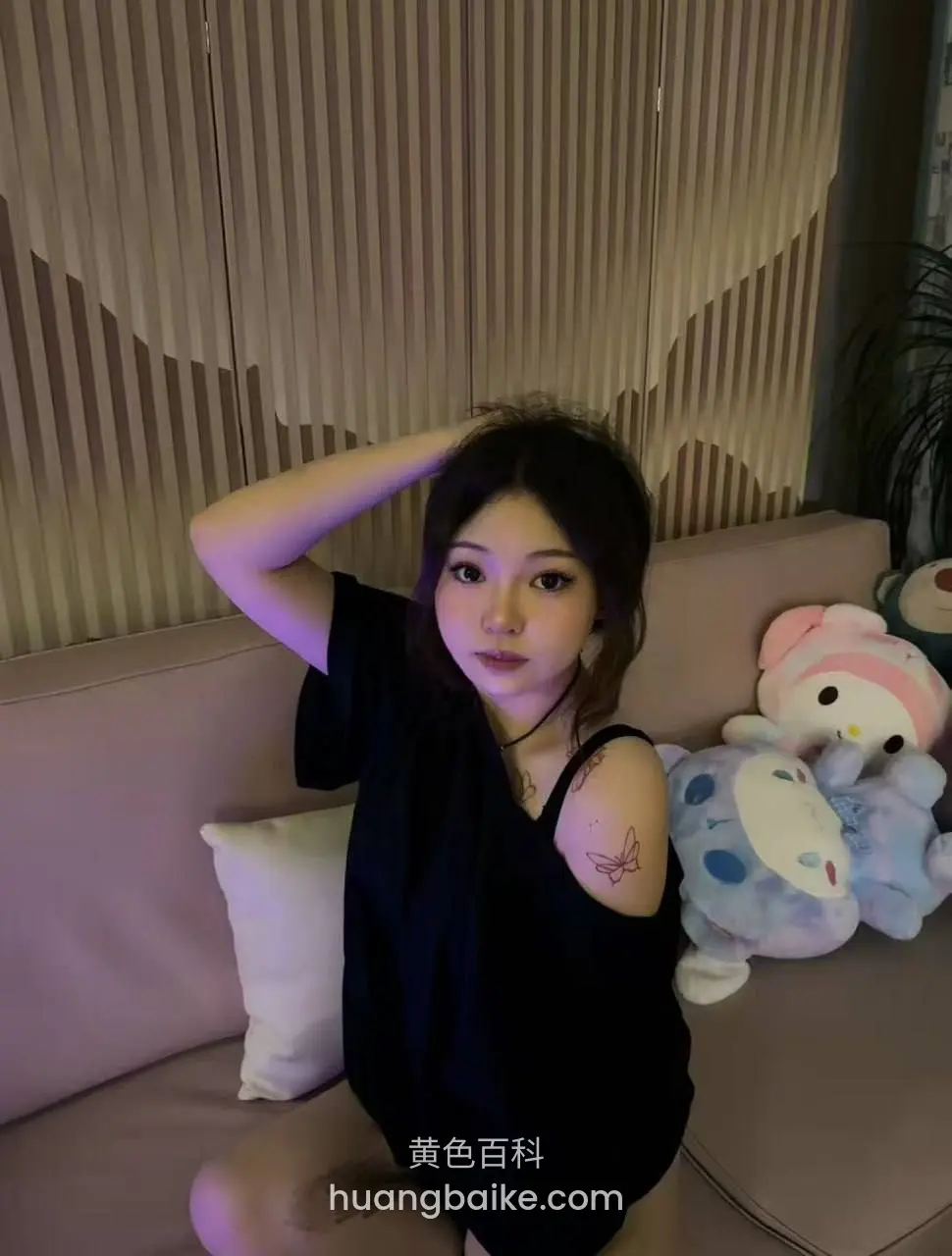 沙发上单手举过头顶，旁边两个大玩偶