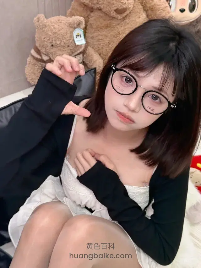 床上眼镜妹比心，身后大熊玩偶