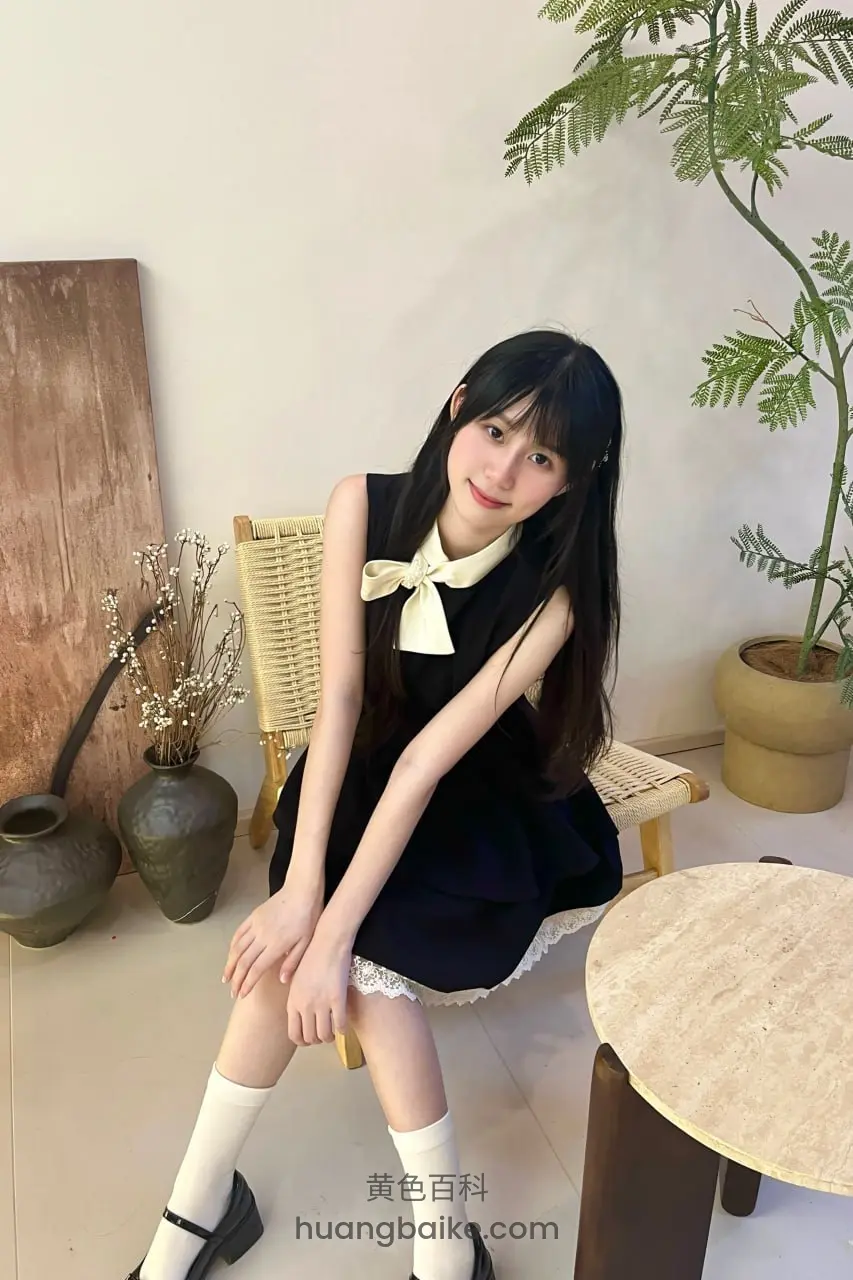 室内植物旁椅子上坐着，手放膝盖