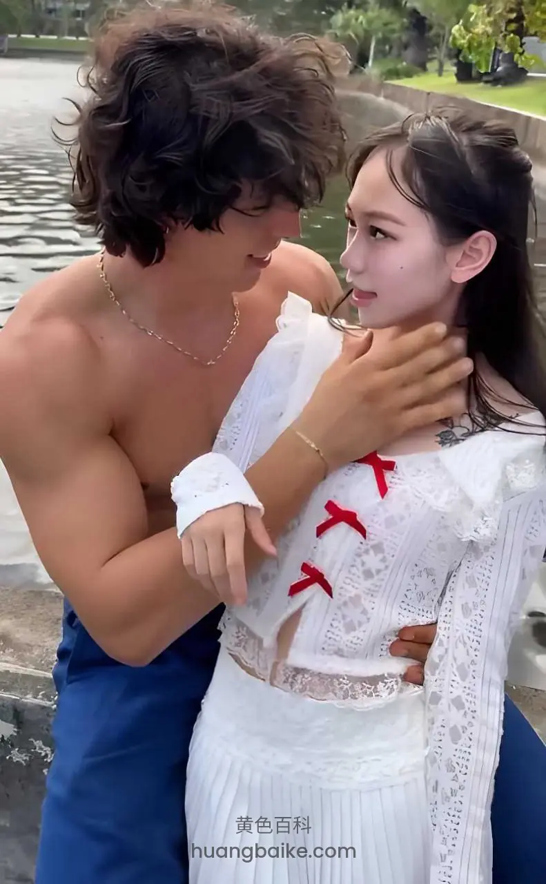 水边搂着脖子看镜头，手指着前方