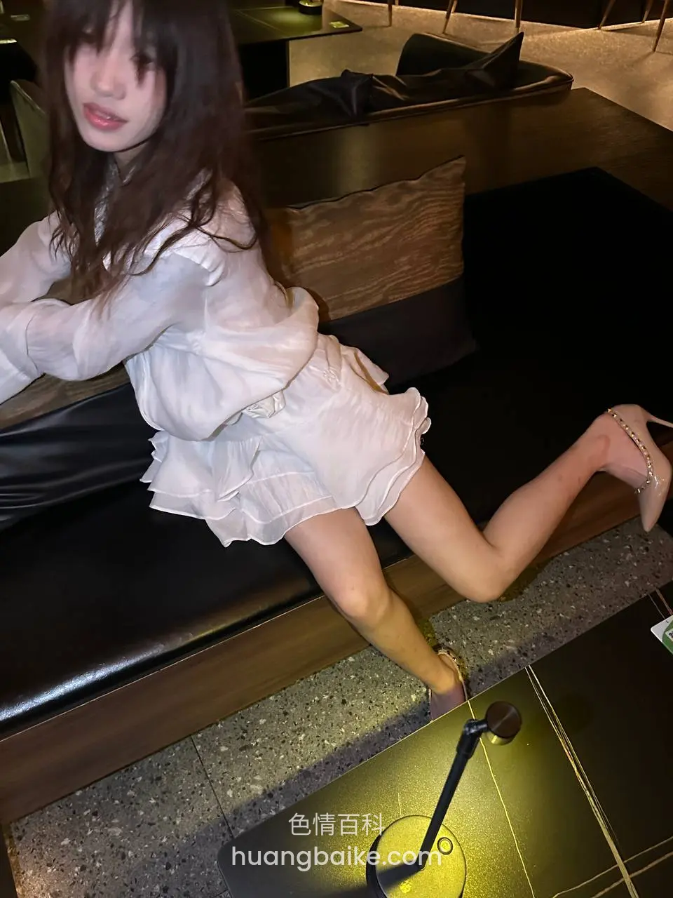 酒吧沙发上翘腿坐着，身后吧台灯亮着