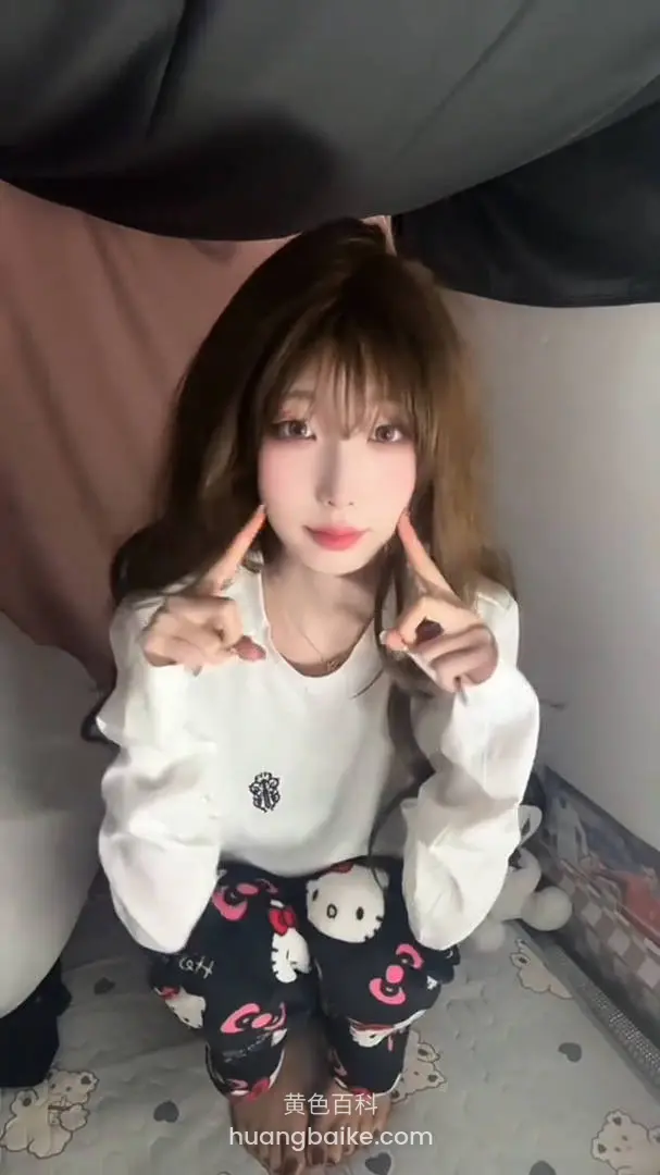 盘腿坐在床上比剪刀手