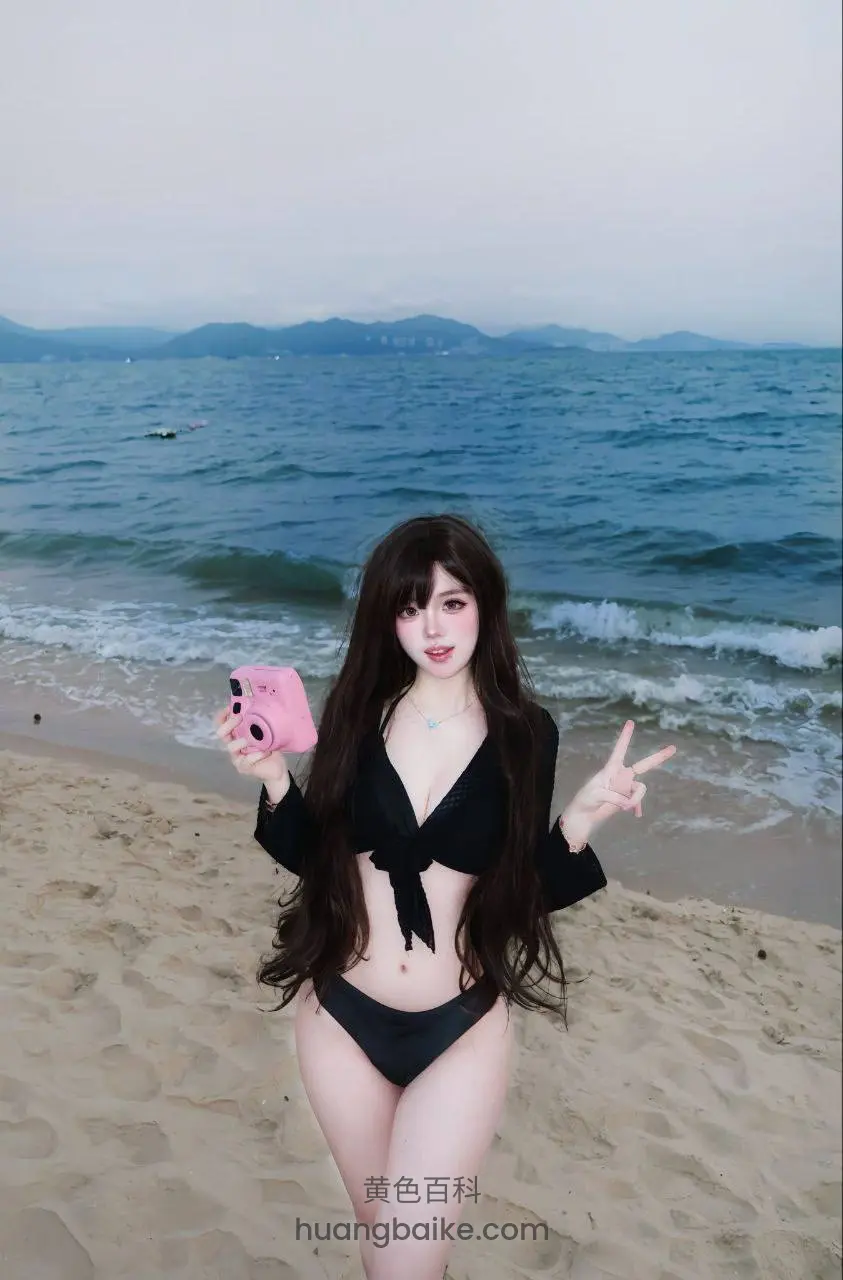 海边沙滩上，举着粉色相机做手势