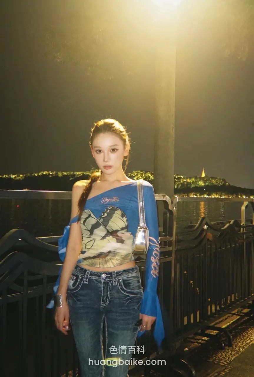夜间河边路灯下站着看镜头，手拿包带