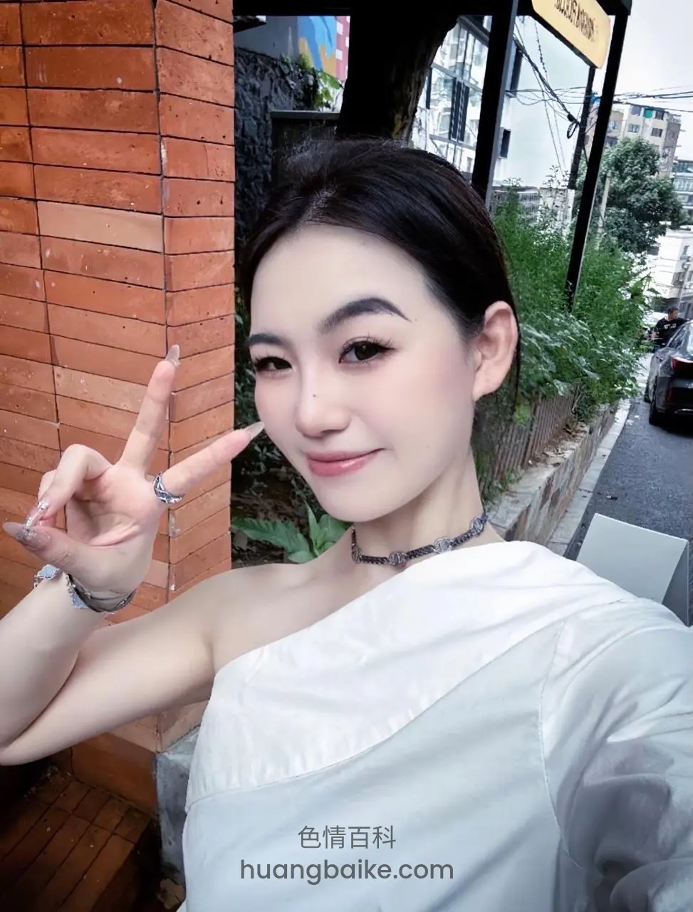 街边靠砖墙自拍，比着剪刀手