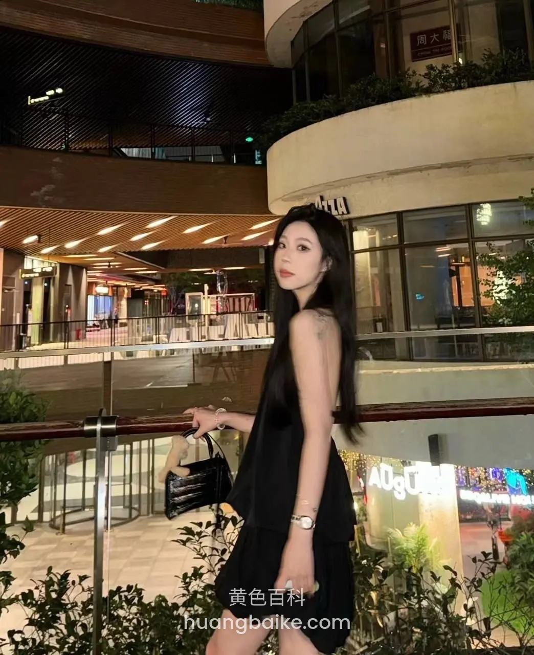商场二楼栏杆边，手提黑包回头看