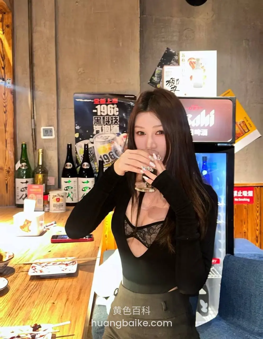 酒吧里拿着玻璃杯喝饮料，桌上摆着酒瓶和菜
