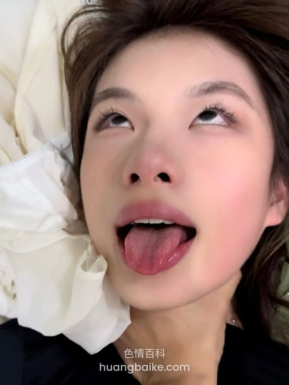 床上躺着伸舌头看上方，旁边白布料