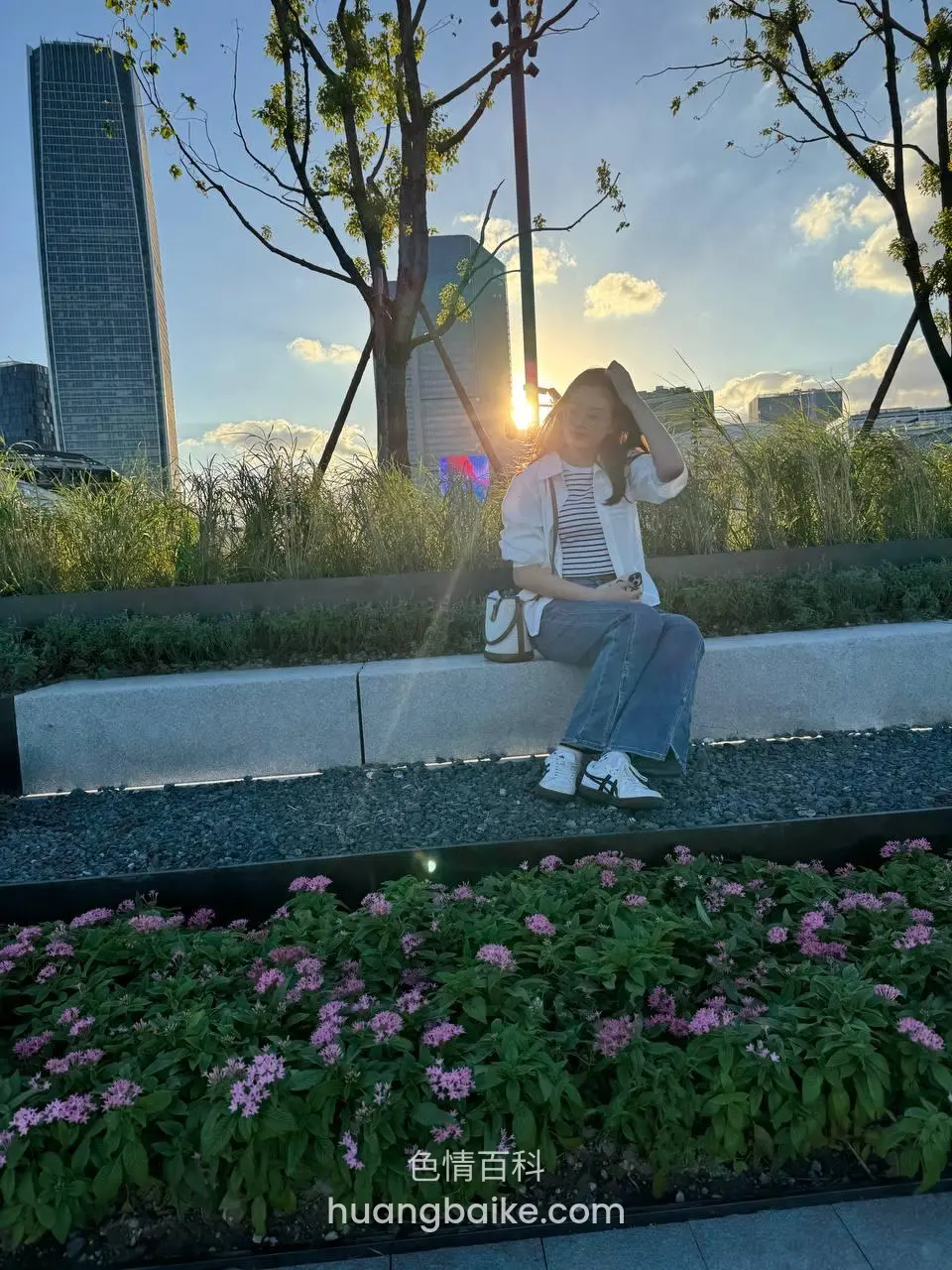 花坛前石阶上坐着，右手举起挡住夕阳光