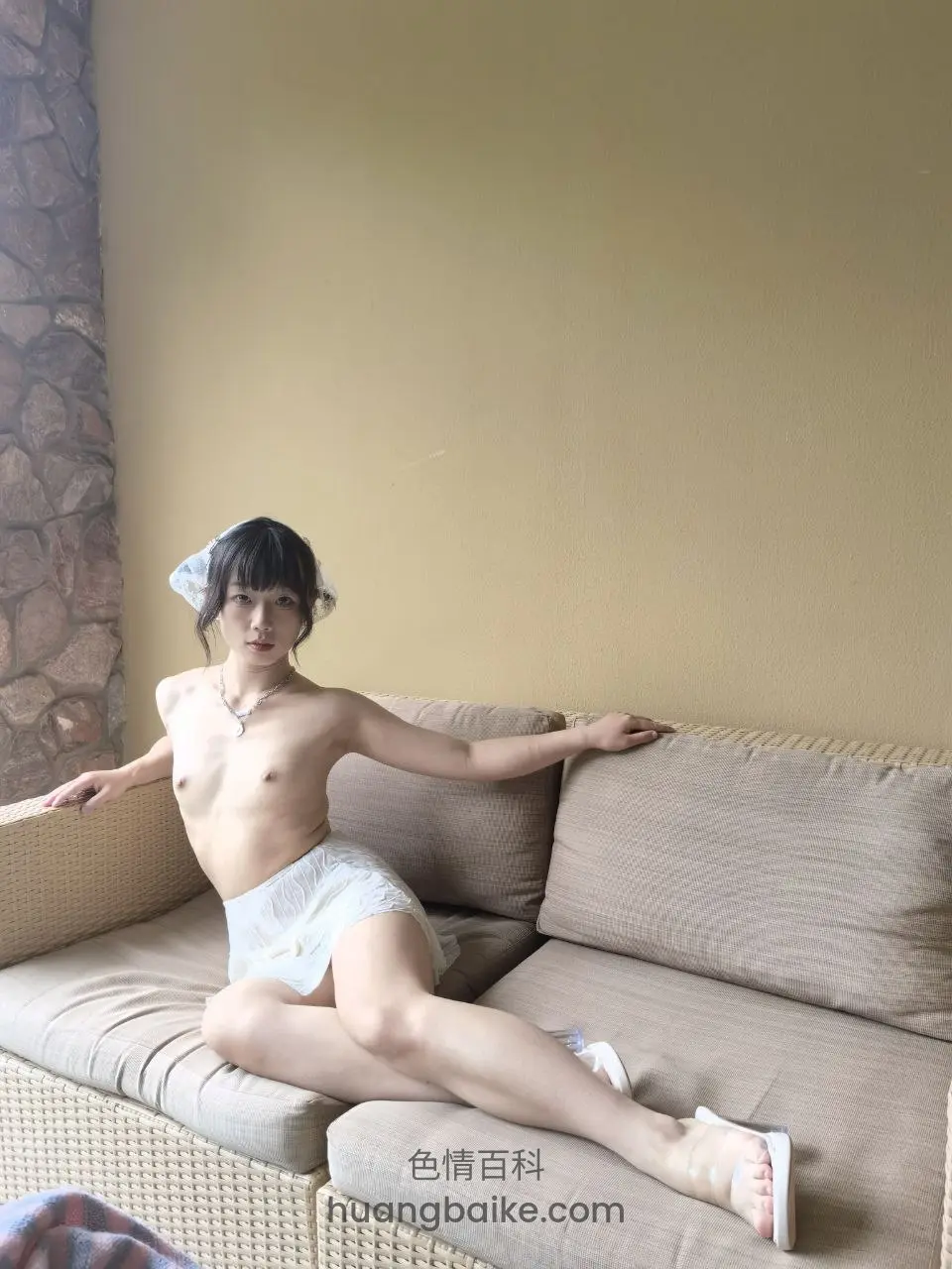 藤编沙发上光上身坐着直视镜头，头戴白蕾丝头纱