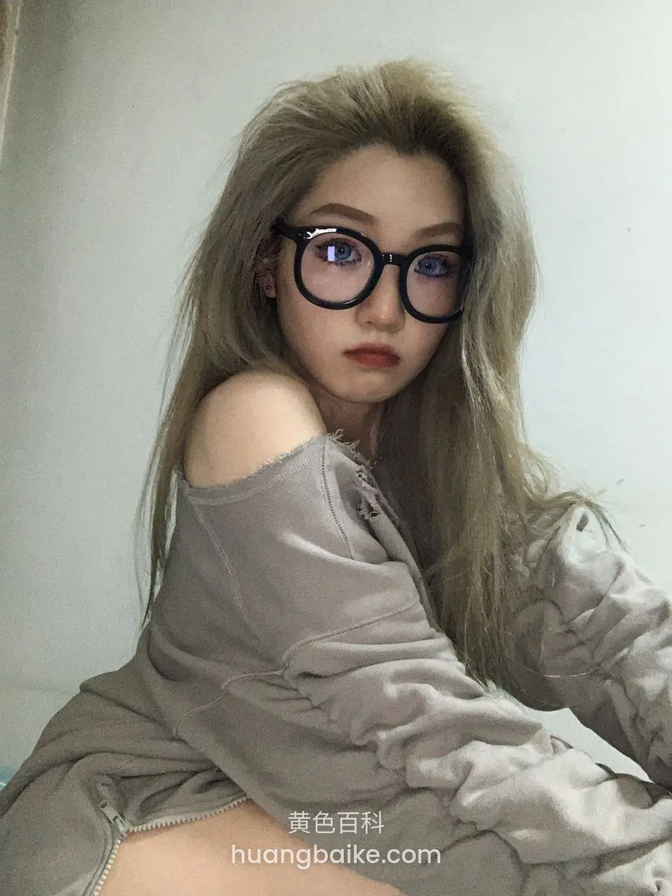 戴黑框眼镜歪头看镜头，肩头露着