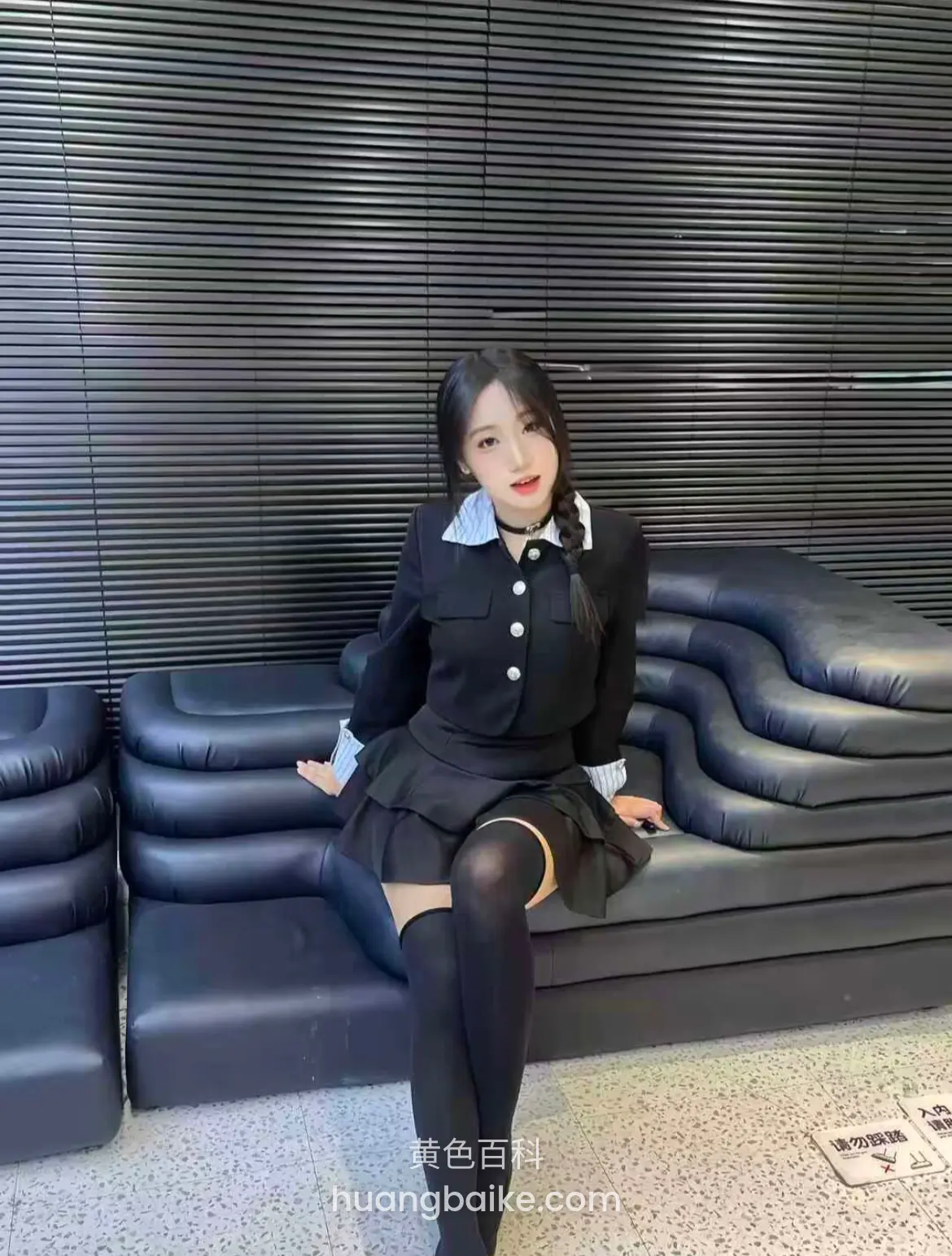 商场黑沙发上坐着，身后是百叶窗