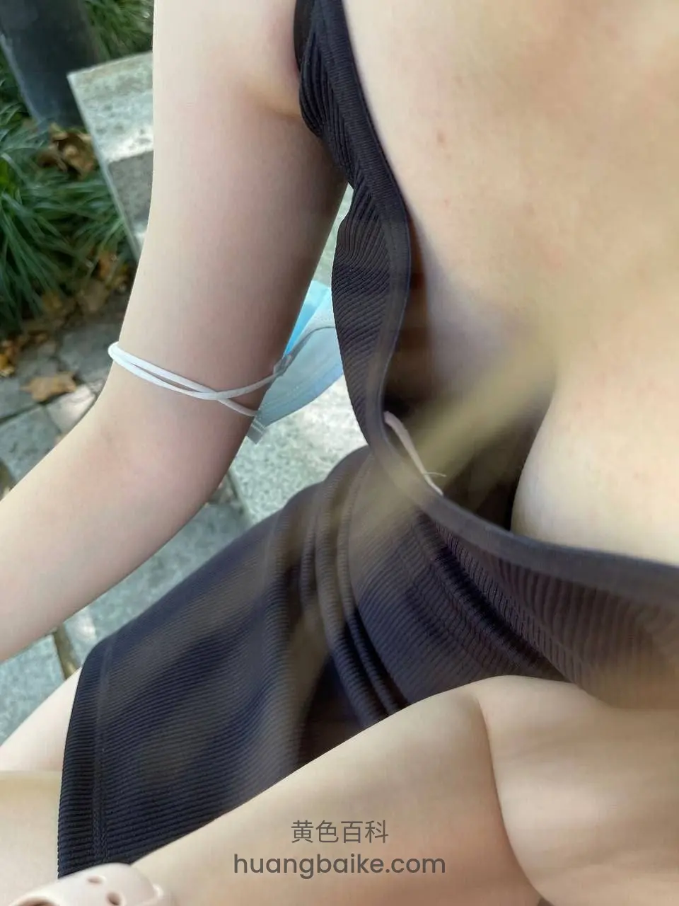 户外穿黑色吊带裙，胳膊戴白色手绳
