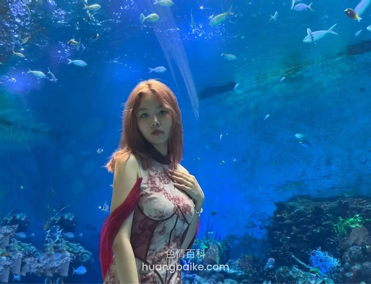 水族馆里手扶胸口，镜头对着身后鱼群