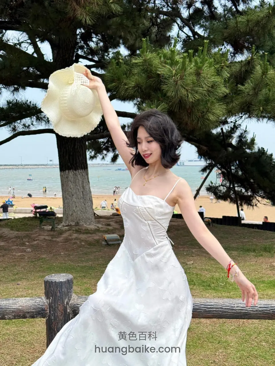 海边草地举着草帽站树下