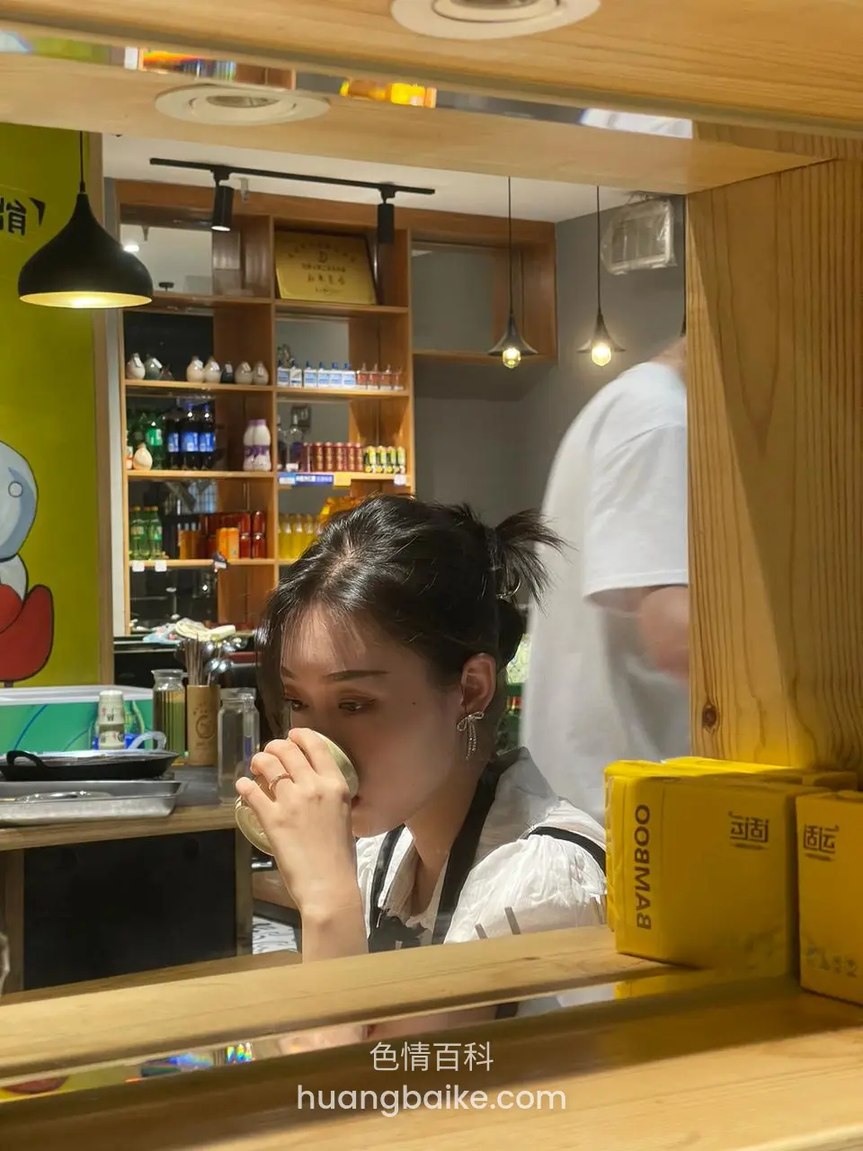 从木框外拍喝饮料，柜台前有黄纸箱
