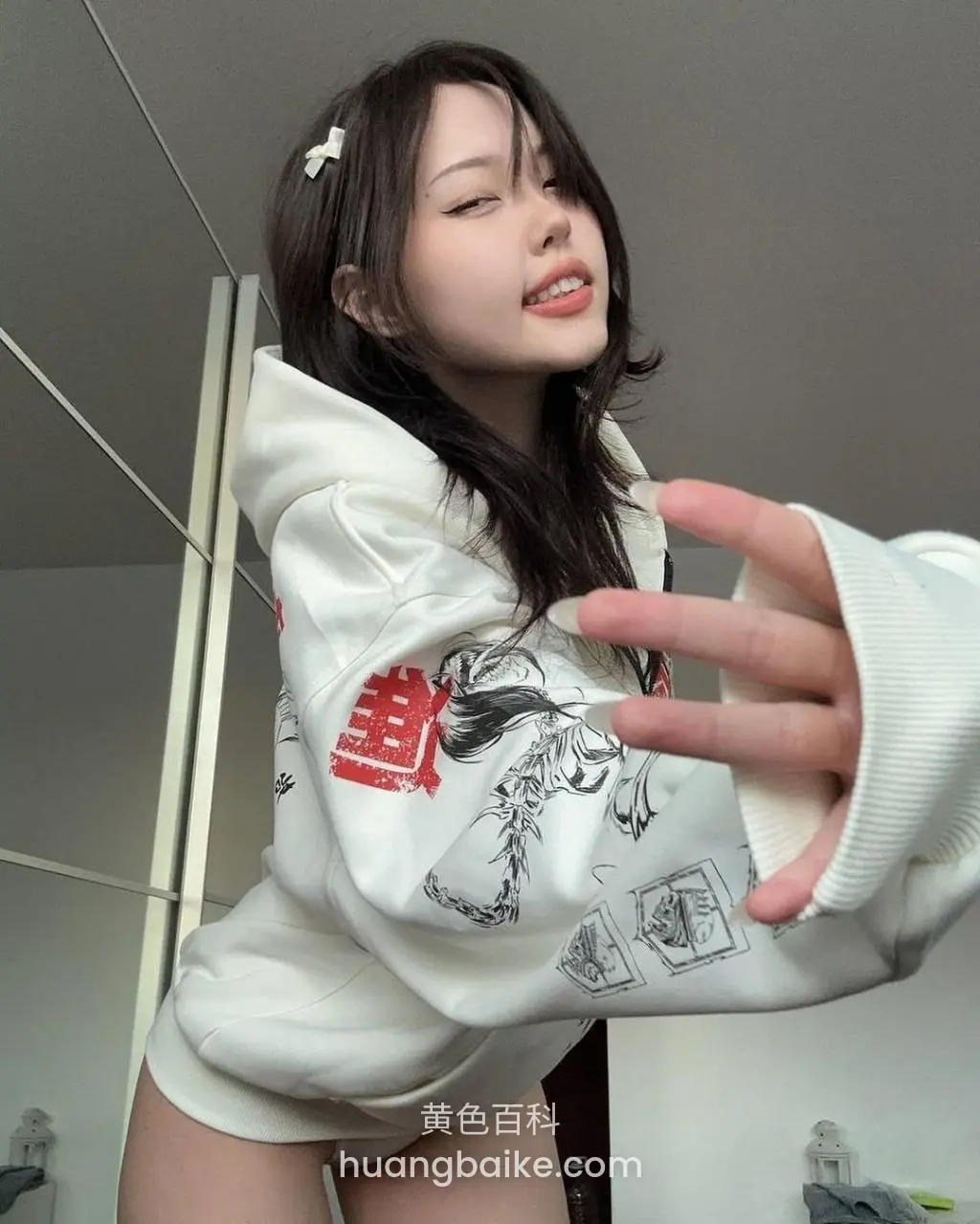 室内举手比剪刀，白色卫衣印图案