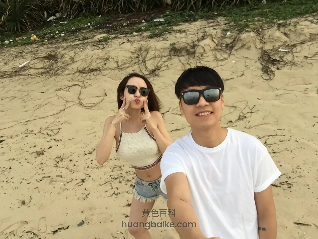 沙滩镜头对着两人，她双手比心
