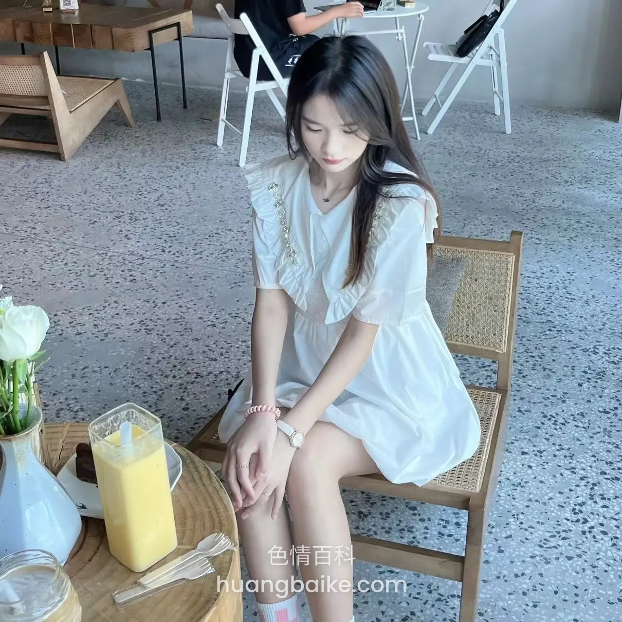 咖啡厅桌边橙汁杯前坐着低头看腿