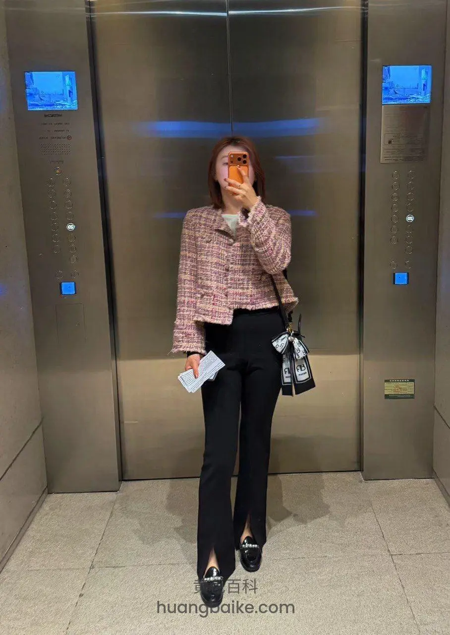 电梯里自拍手机挡脸，手里拿着纸片和包