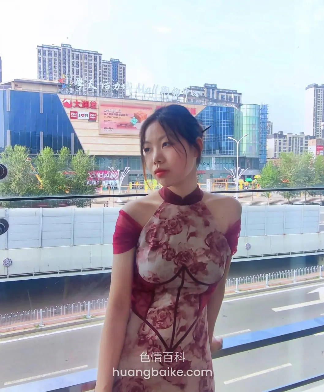 城市高架桥上站着看镜头，身后是商场大楼和公路
