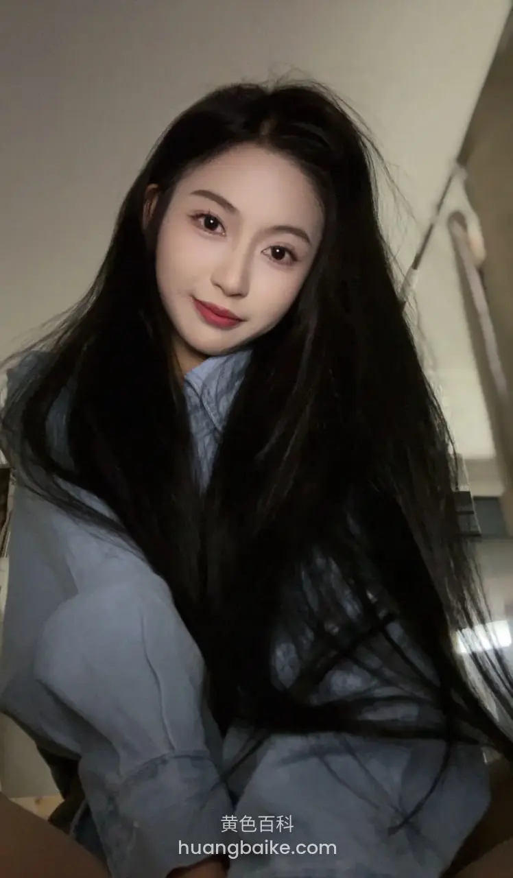 侧身低头看镜头，左手抓着长发