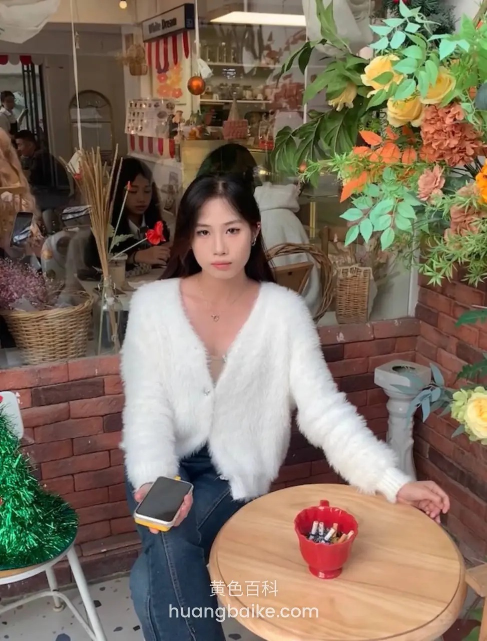 咖啡店圆桌边拿着手机，桌上红色小桶里插吸管