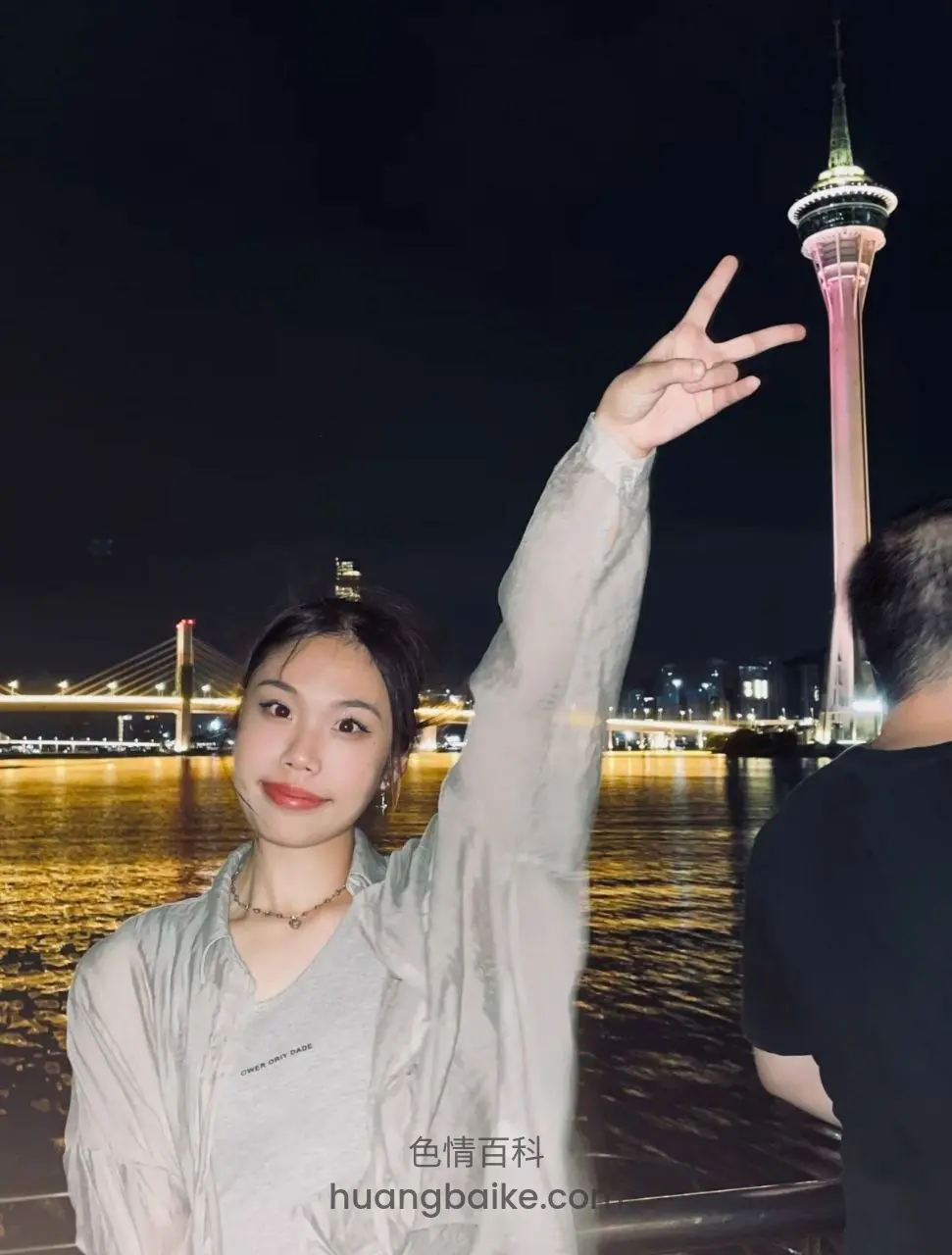 夜景河边举手比剪刀手，澳门塔在身后