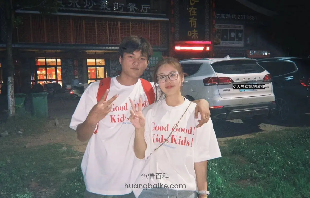 夜间停车场，两人比剪刀手，身后有餐厅招牌