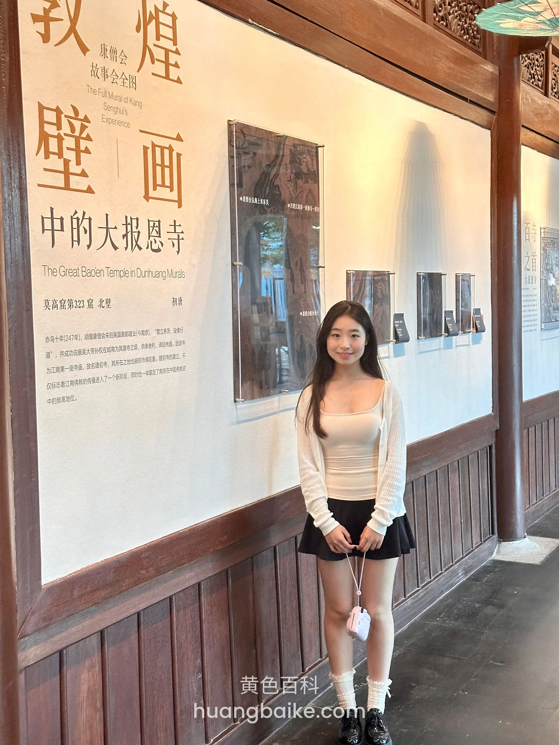 展板前站立，手拿小包垂在身前