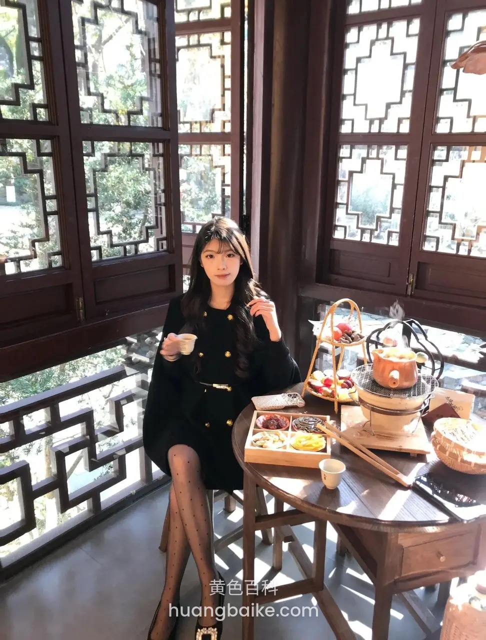 中式茶室里端着杯子看镜头，桌上热气腾腾火锅