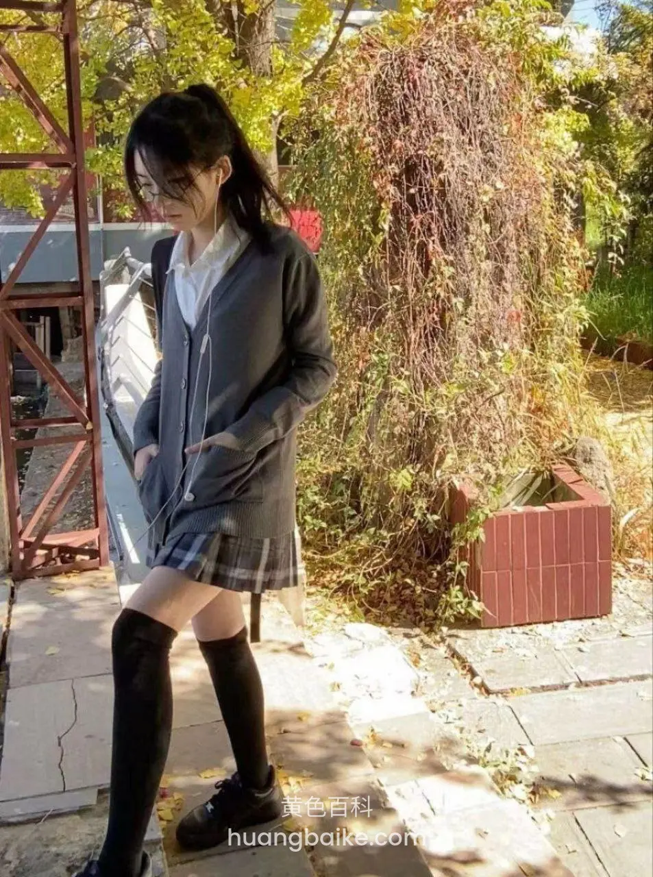 户外藤蔓墙边，手插口袋站立