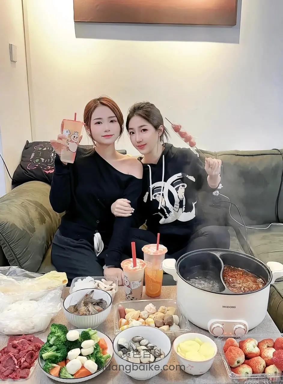 客厅沙发上两人比耶，面前摆着火锅和菜