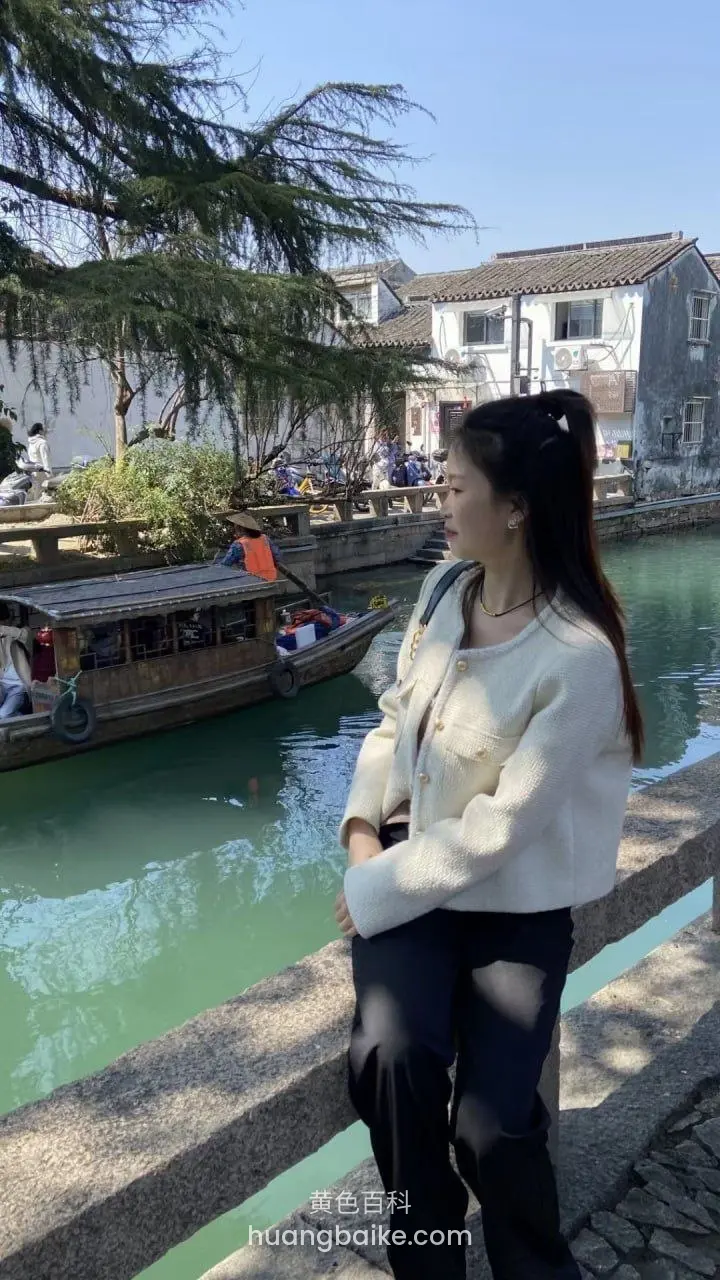 河边石栏杆旁,河里有船和古建筑