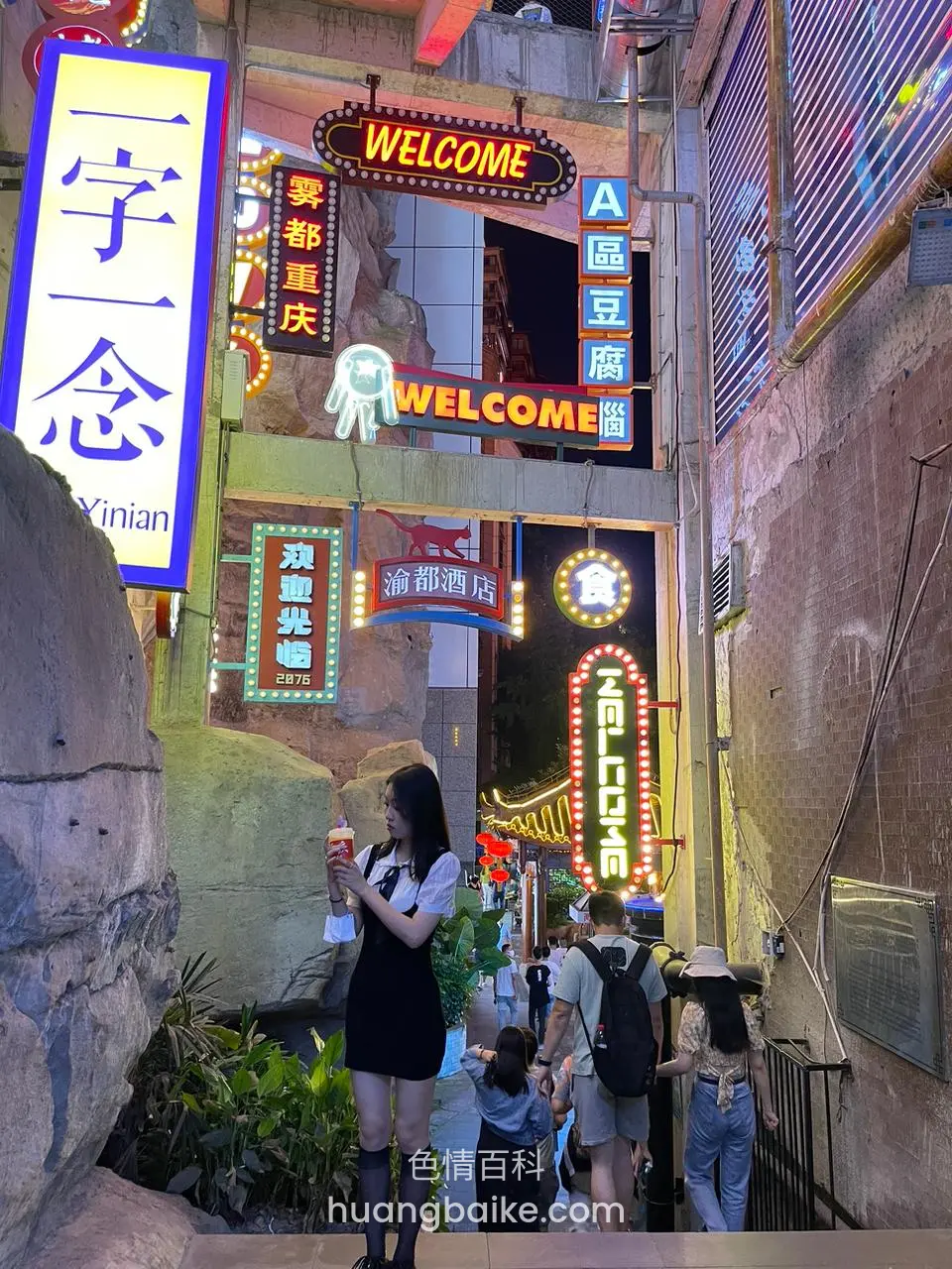 夜市巷口举着饮料看手机，身后霓虹招牌