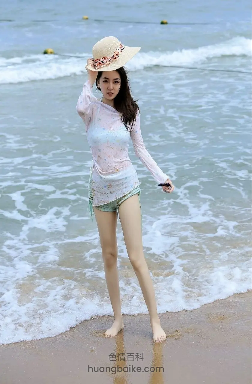 海边浪花中站立，手扶草帽看海